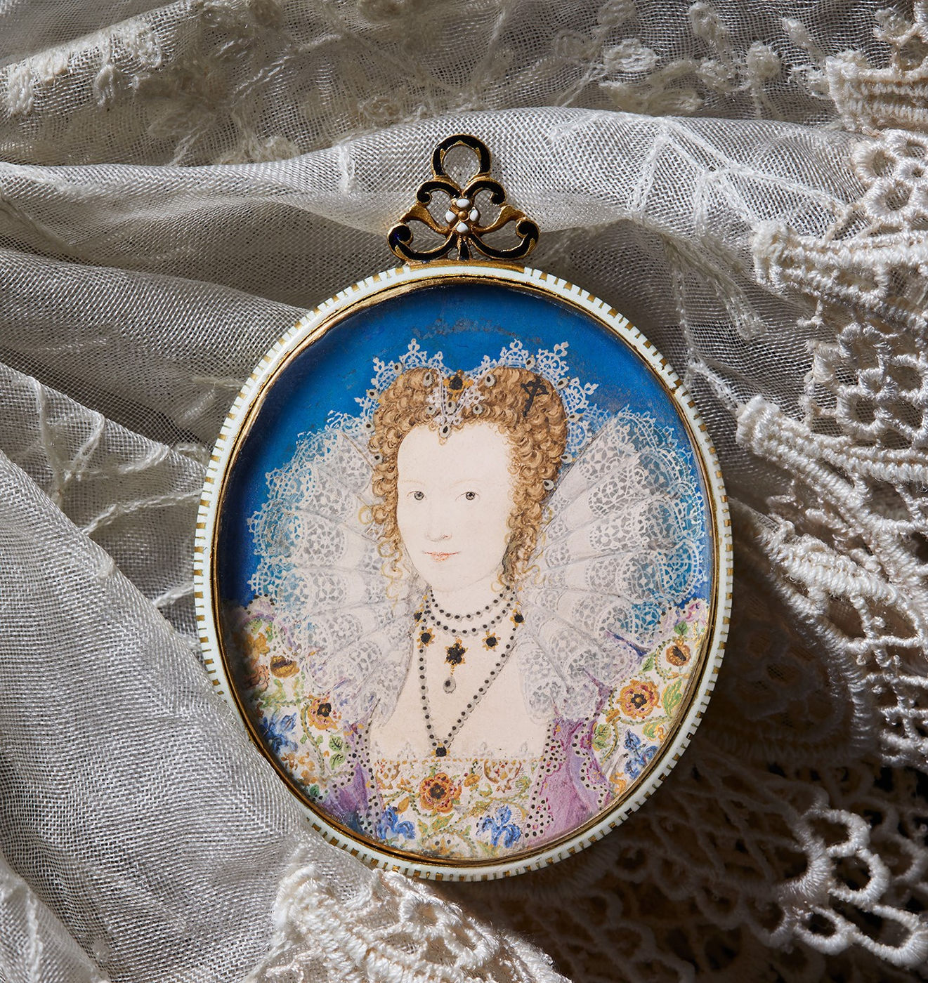 A portrait miniature of a Tudor Lady in Court. She wears a large lace ruff, with a floral dress against a bright blue backgound This artwork by Nicholas Hilliard has sold.